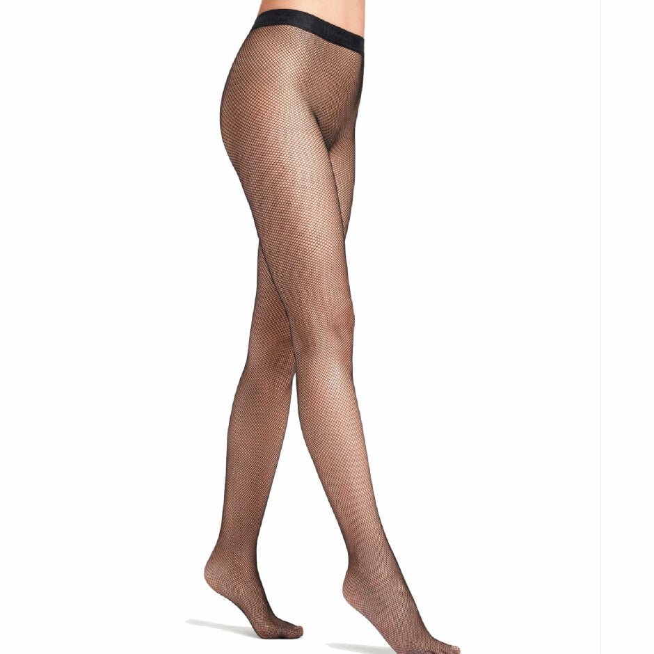 En person iført et par Wolford Twenties Econyl-strømpebukser i sort, størrelse W, står på tå foran en hvid baggrund. Der ses ingen sko.
